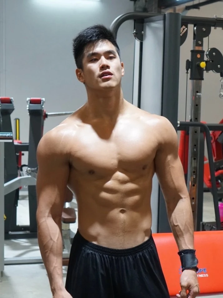 Alex Chee 赤膊站在训练器械前，展示胸腹和肩臂肌肉；本人十年变化帖中的历史照片