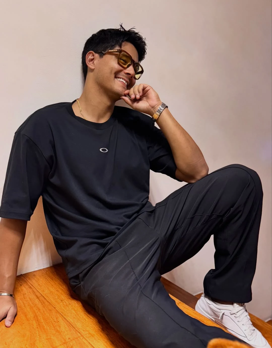 Daniel Matsunaga 戴墨镜、穿黑色运动套装坐在椅子上