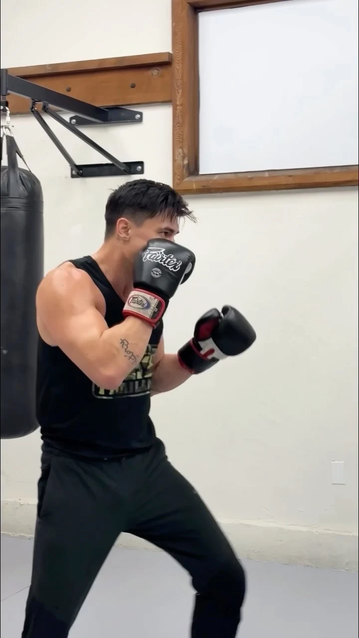 Lewis Tan 穿黑色背心、戴拳套练拳，展示肩臂线条；本人公开视频静态封面